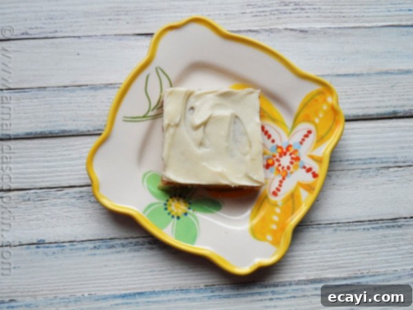 Luscious Banana Bars with Velvety Vanilla Frosting 4 An overhead shot of a single banana bar on a plate, showcasing the thick vanilla cream cheese frosting.