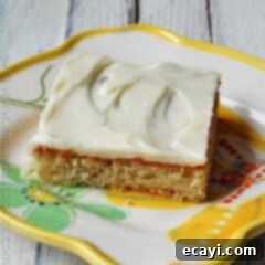 Luscious Banana Bars with Velvety Vanilla Frosting 8 A close up photo of a banana bar with vanilla cream cheese frosting on a white plate.