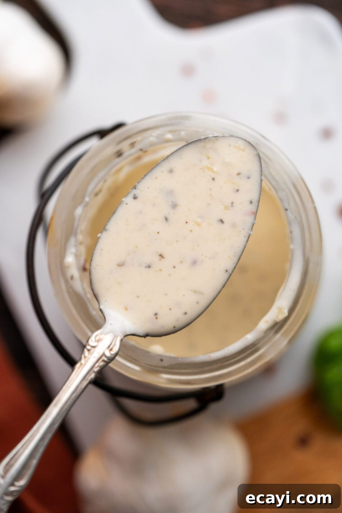 Ultimate Garlic Parmesan Wing Sauce 11 Spoon of Garlic Parmesan Wing Sauce held above a jar of sauce