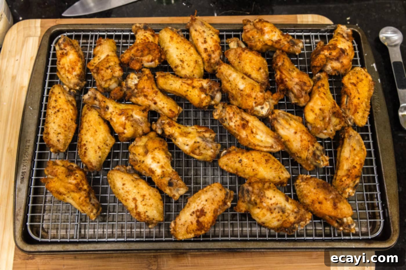 Crispy Garlic Parmesan Wings 14 Crispy fried chicken wings resting on a cooling rack to drain oil