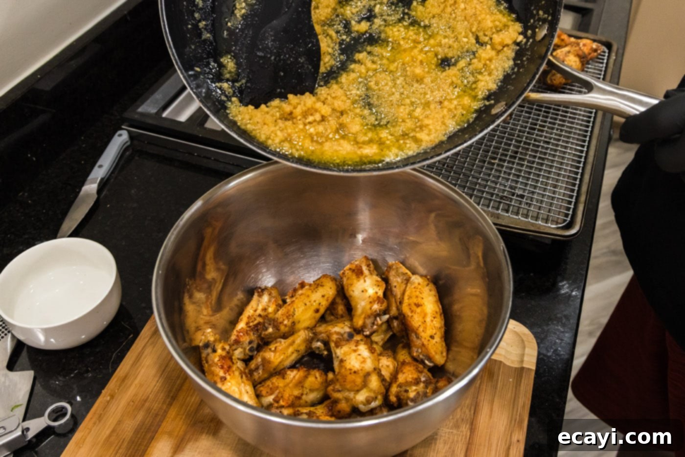 Crispy Garlic Parmesan Wings 15 Pouring homemade garlic parmesan sauce over crispy chicken wings in a bowl