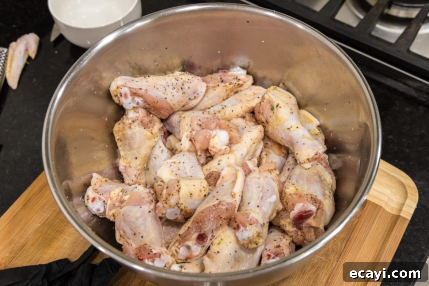 Crispy Garlic Parmesan Wings 6 Close-up of seasoned chicken wings being tossed in a bowl