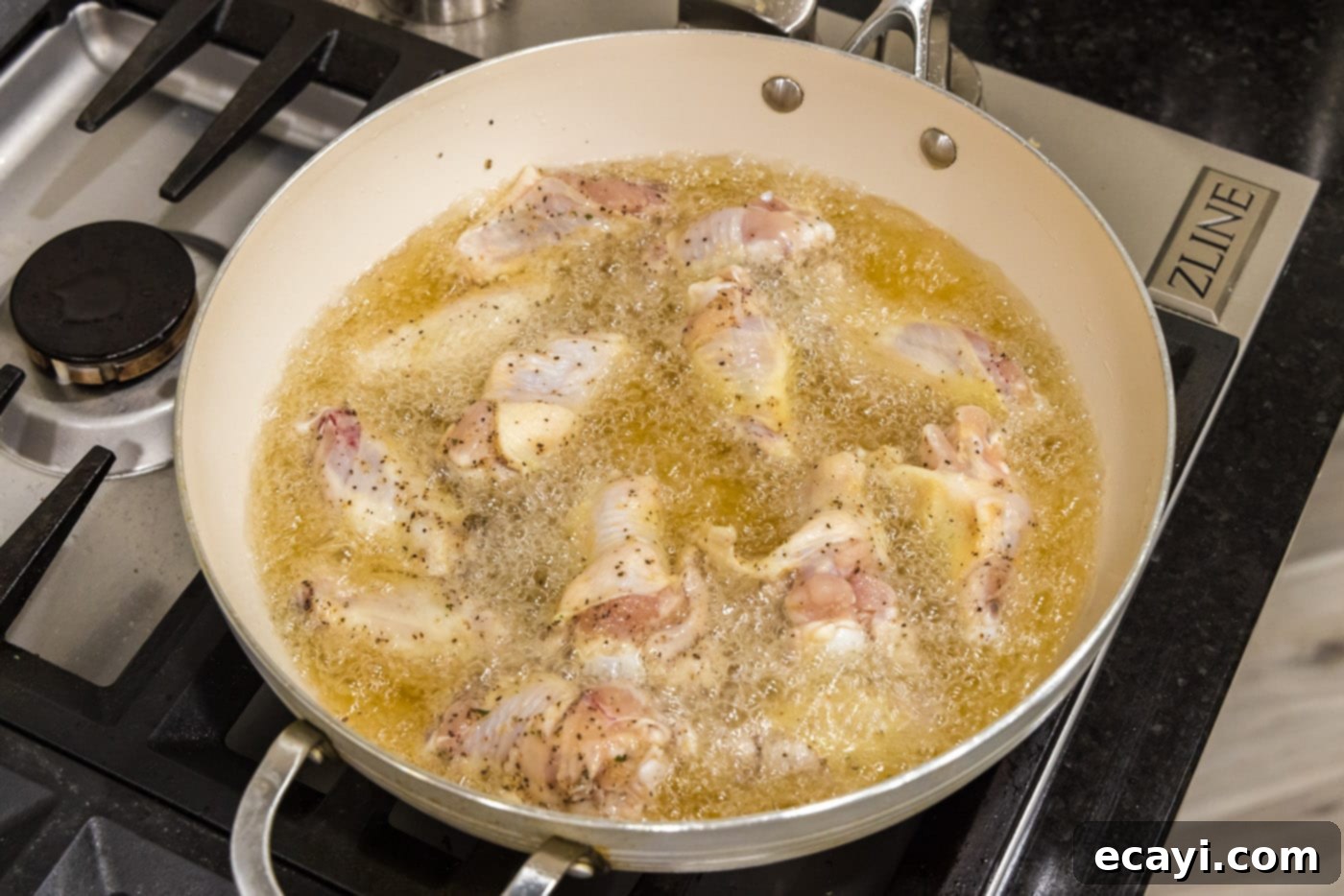 Crispy Garlic Parmesan Wings 7 Chicken wings frying in hot oil in a skillet