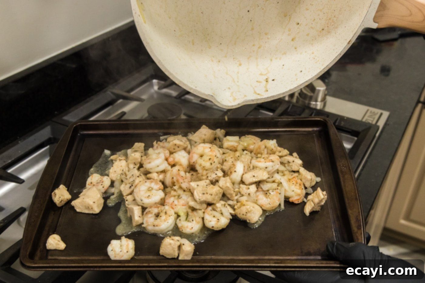 Surf and Turf Carbonara 8 pouring chicken and shrimp mixture onto a baking sheet