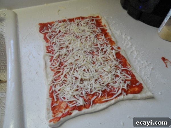Pizza Pinwheels 8 Pizza dough covered with sauce and cheese, ready to be rolled up.