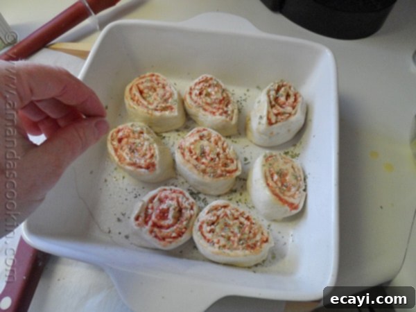 Pizza Pinwheels 10 Sliced pizza roll ups arranged in a baking pan, brushed with butter and seasoned.