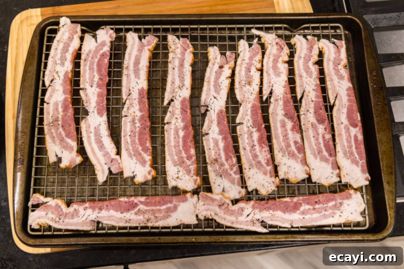 Bacon Green Bean Bundles 5 Bacon strips laid on a wire rack seasoned with Montreal steak seasoning