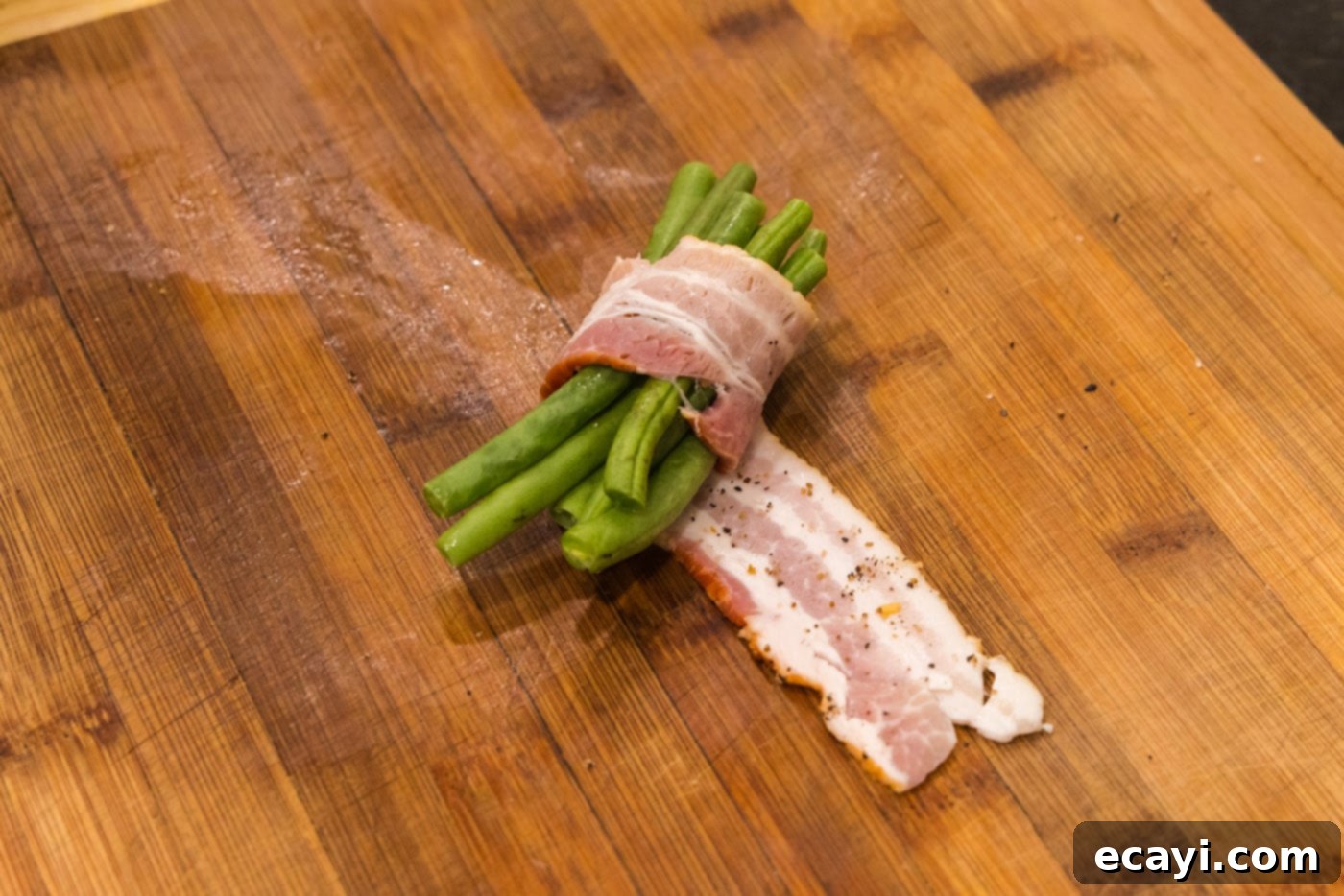 Bacon Green Bean Bundles 6 Step-by-step photo of wrapping a bundle of fresh green beans in a seasoned bacon strip