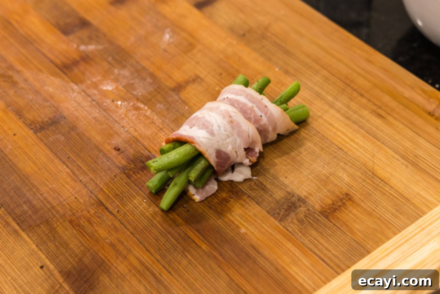 Bacon Green Bean Bundles 7 Close-up of bacon wrapped green beans placed on a baking sheet with a wire rack