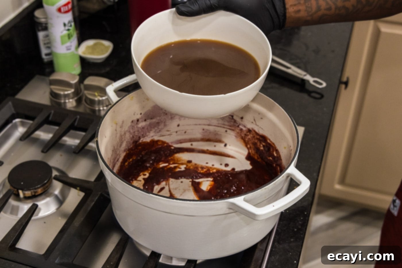 Fork-Tender Beef Short Ribs 12 pouring beef broth into red wine and tomato paste mixture