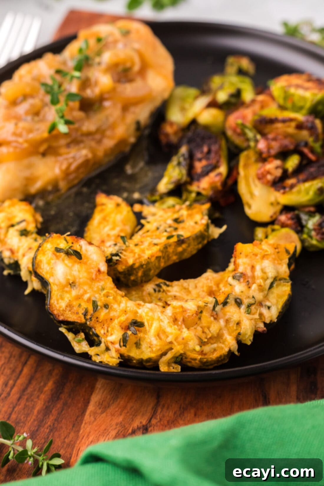 Delicious Air Fryer Acorn Squash 16 Close up photo of Air Fryer Acorn Squash on a plate with Brussels sprouts and chicken