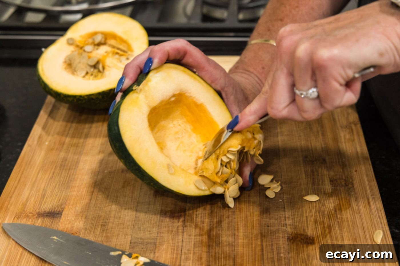 Delicious Air Fryer Acorn Squash 7 scooping the seeds out of an acorn squash with a spoon