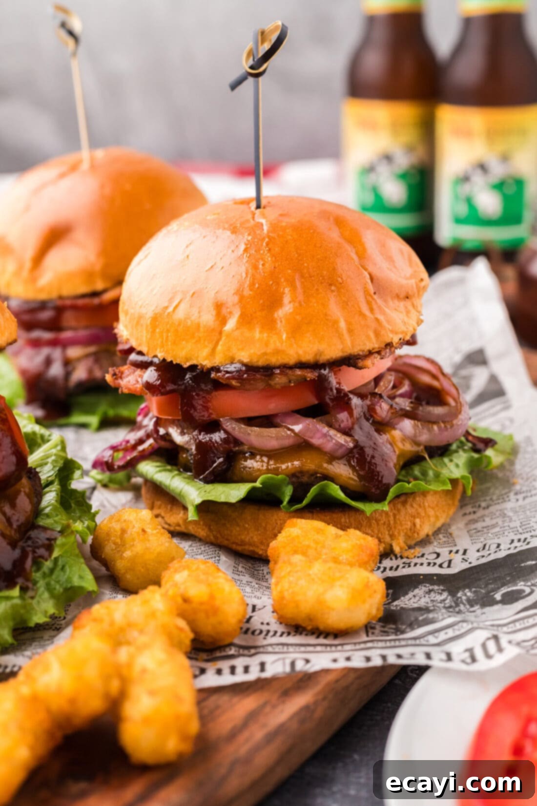 Smoky BBQ Bacon Burgers 2 BBQ Bacon Burgers on a wooden board with tater tots
