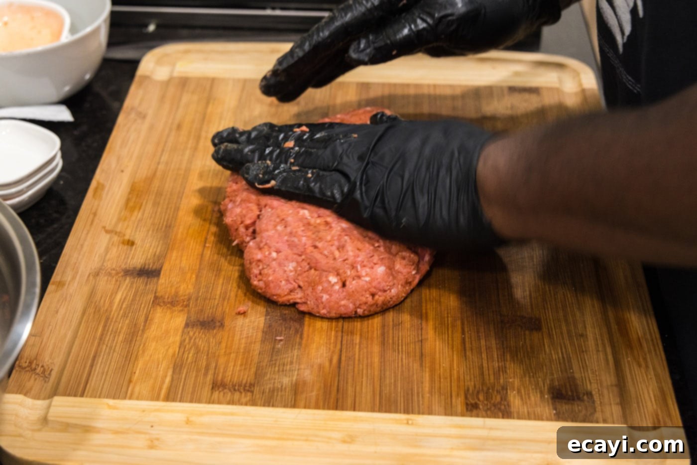 Smoky BBQ Bacon Burgers 5 hands flattening burger meat on a cutting board