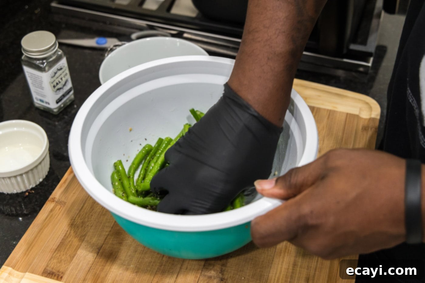 Crispy Air Fryer Green Beans 6 A hand tossing fresh green beans with the oil and seasoning mixture in a large bowl.
