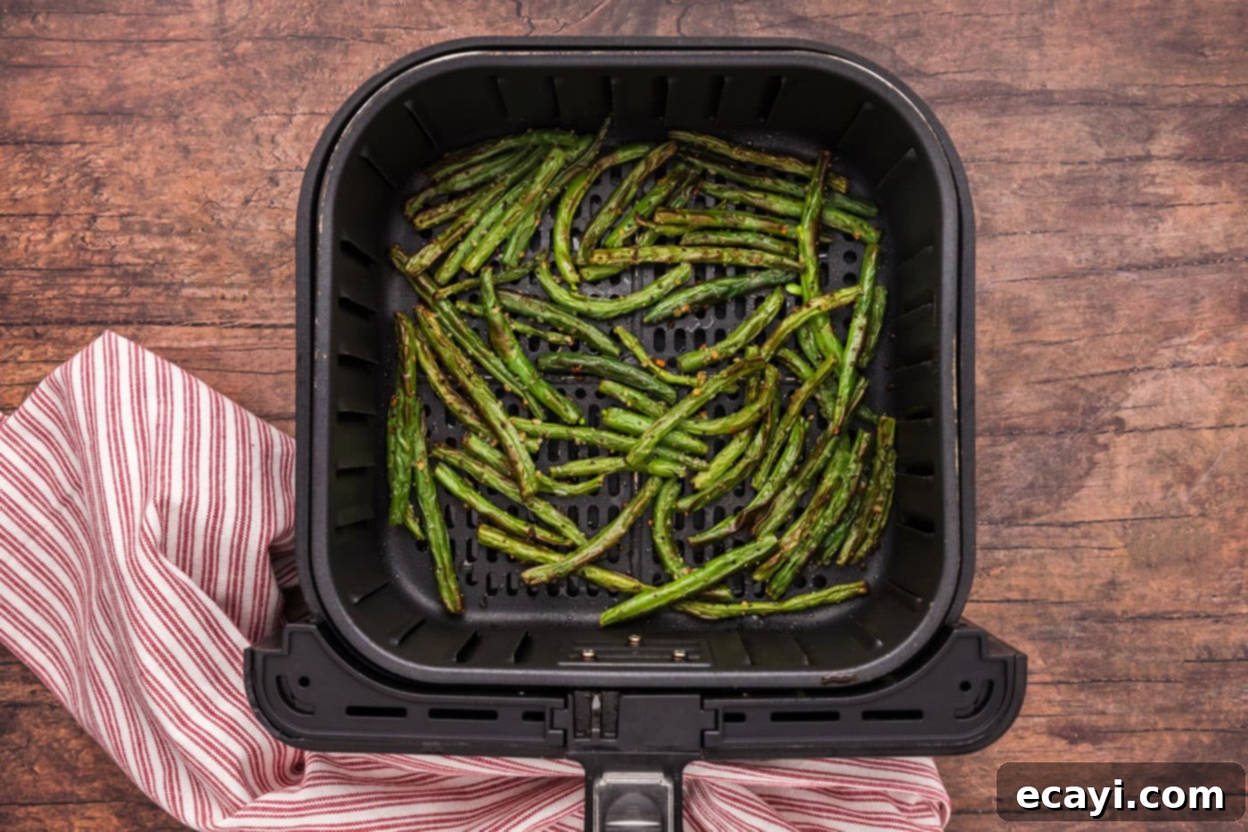 Crispy Air Fryer Green Beans 8 The air frying process showing green beans cooking in the basket, halfway through, being shaken for even cooking.