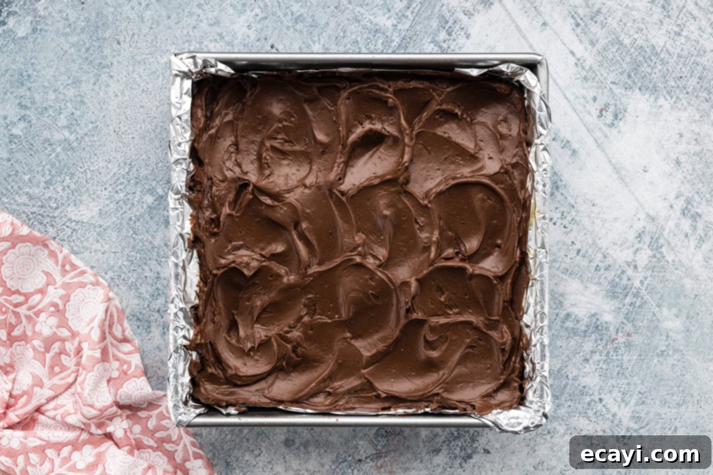 Decadent Espresso Fudge Brownies 10 Fudge frosting being spread smoothly over the cooled espresso brownies in a baking pan, creating an even layer