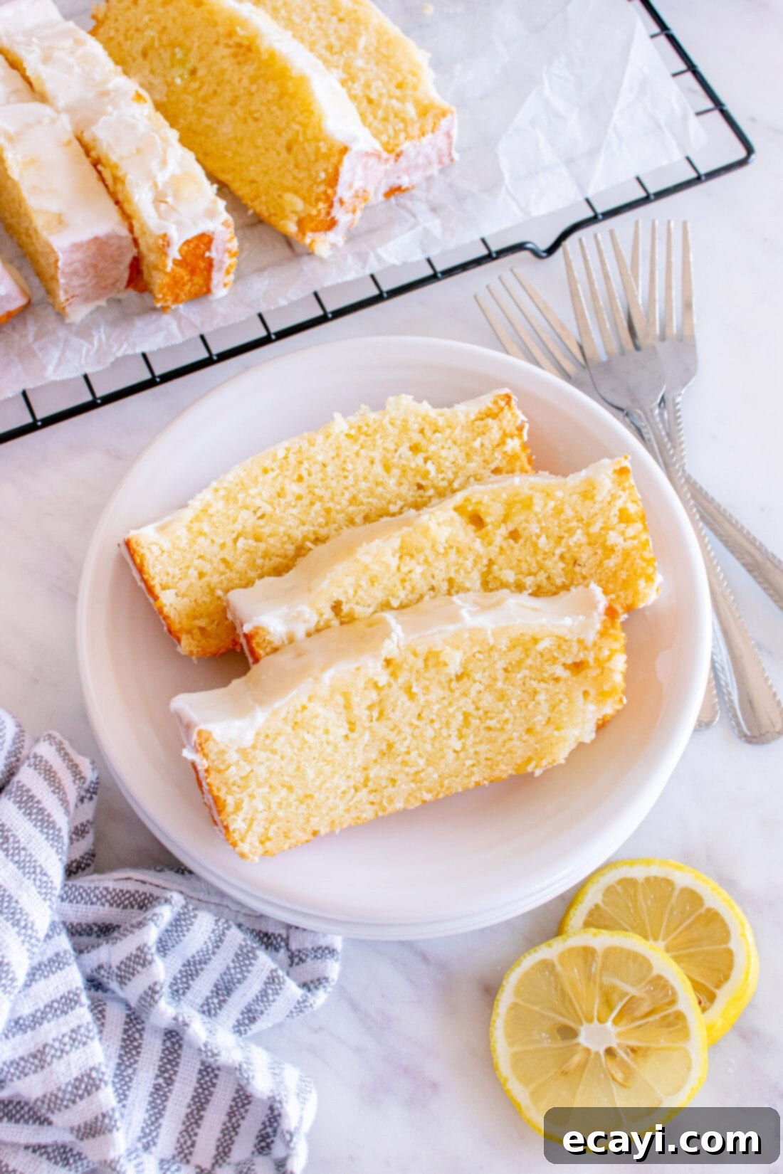 Zesty Lemon Loaf 2 Three slices of Lemon Pound Cake on a plate with more slices in the background, showcasing its tender crumb and glistening glaze.