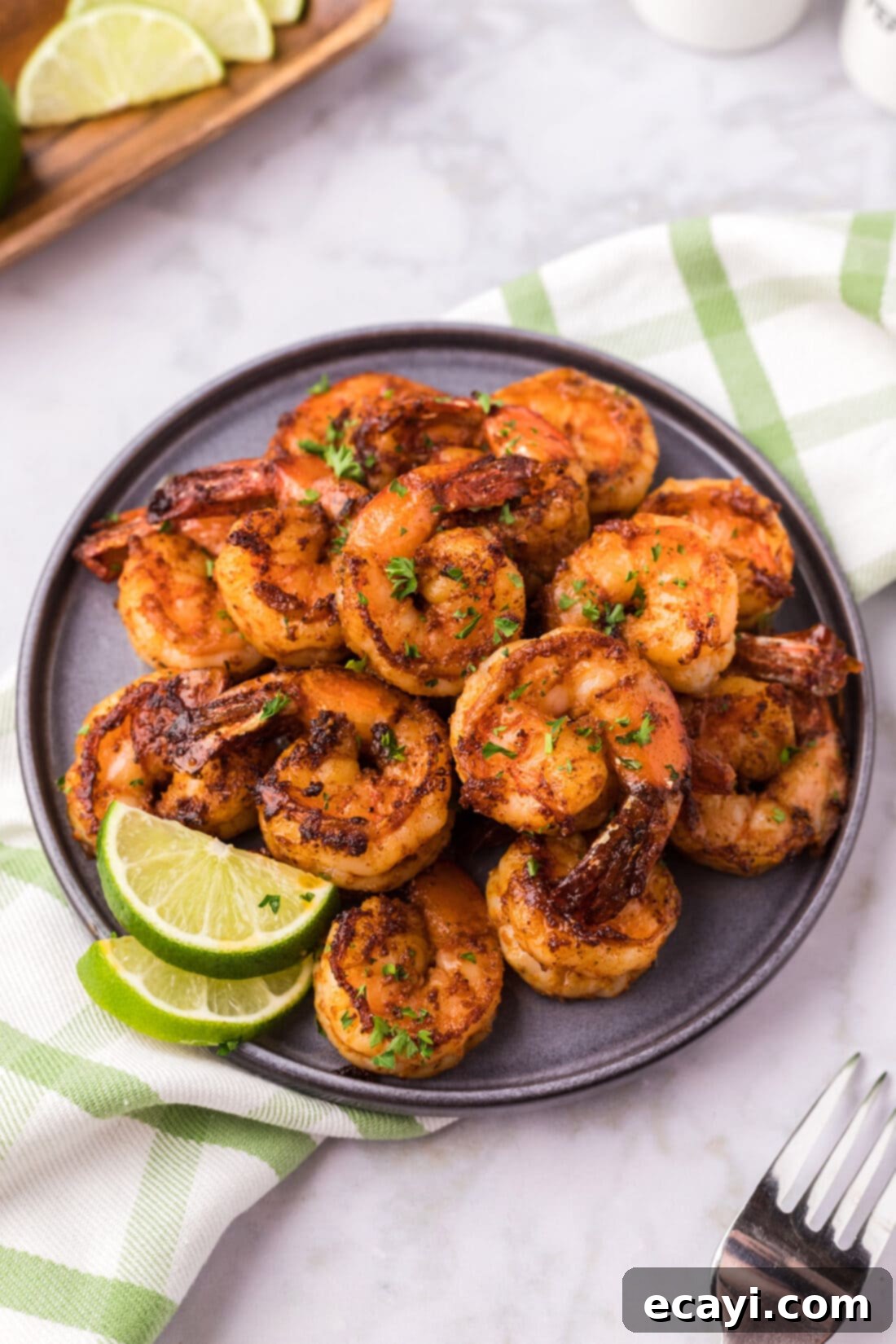 Fiery Prawns 3 Plate of perfectly cooked Spicy Shrimp, garnished with lime wedges and fresh herbs.
