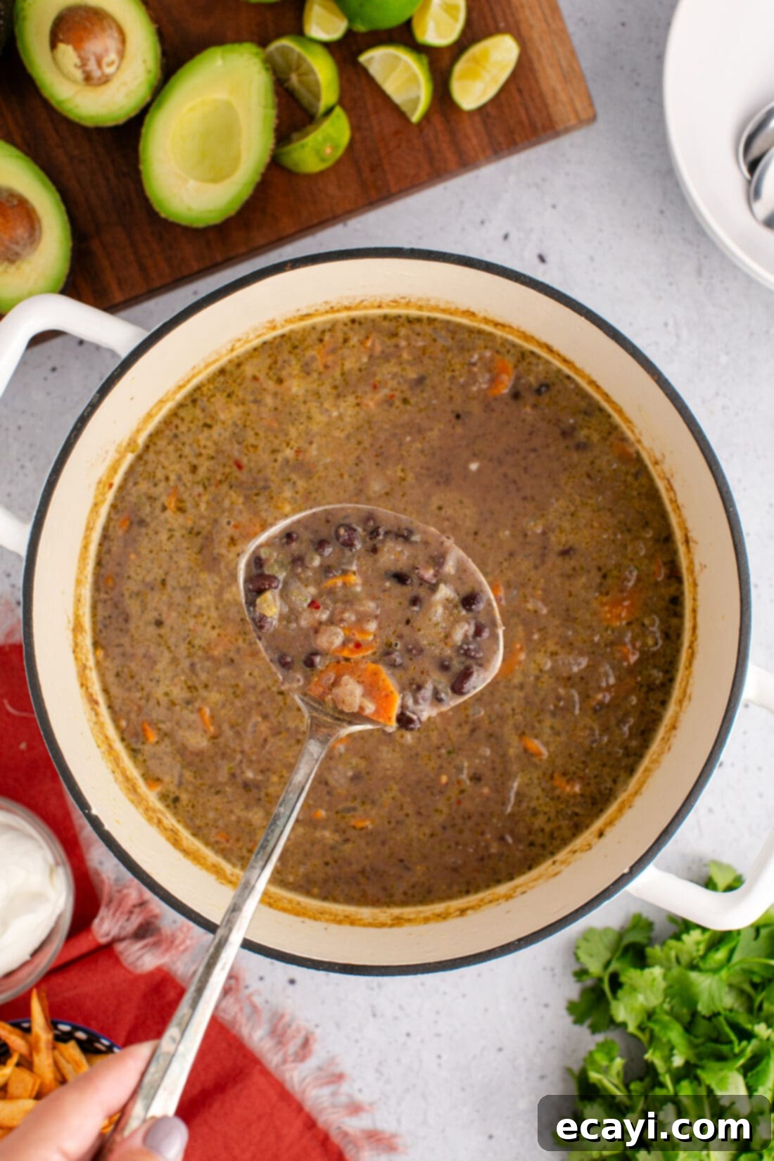 Savory Black Bean Delight 14 A ladle gracefully holding a spoonful of black bean soup above a large pot, showing the rich, dark, and thick consistency of the homemade soup.