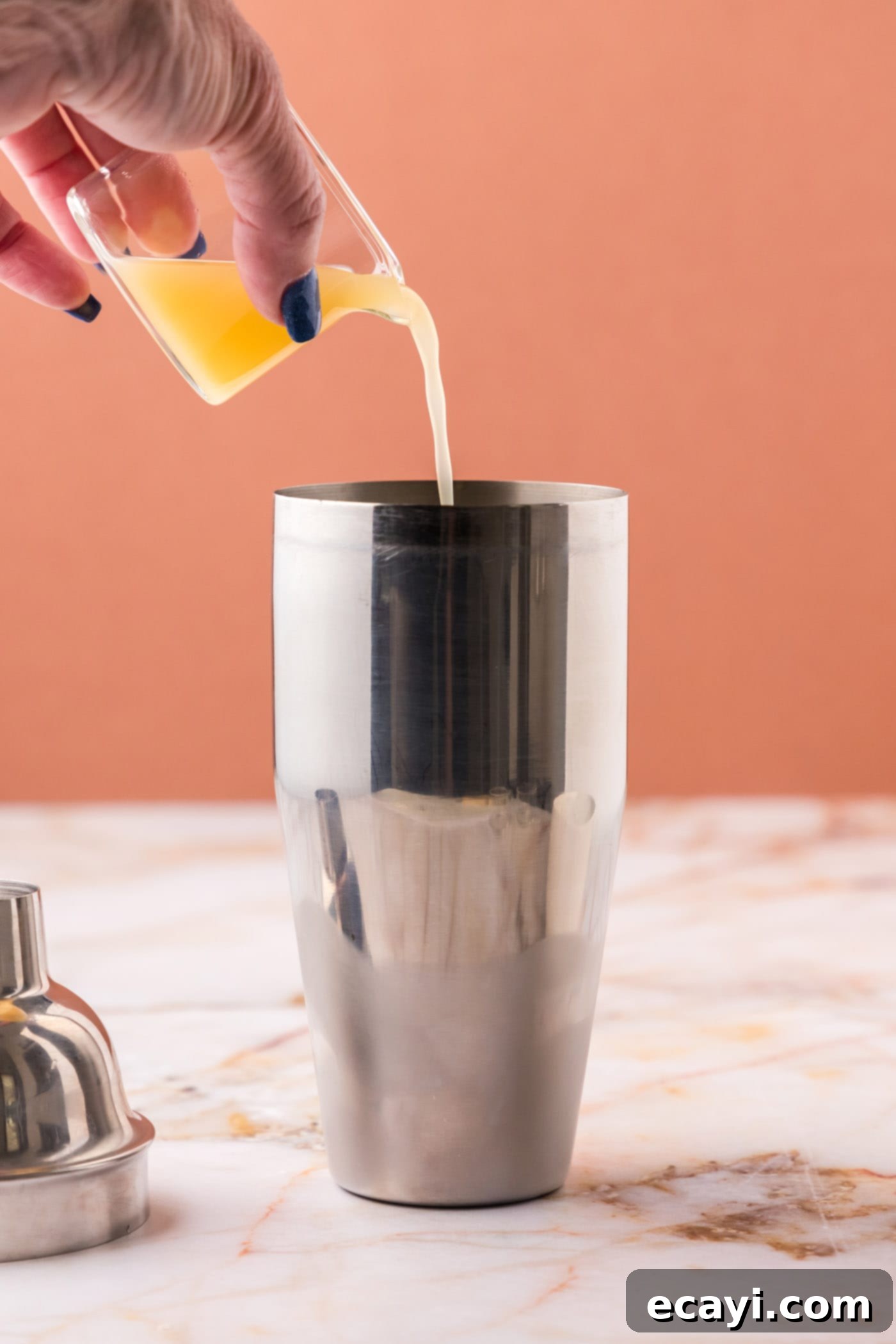 The Parisian Raspberry Sip 7 pouring pineapple juice into cocktail shaker