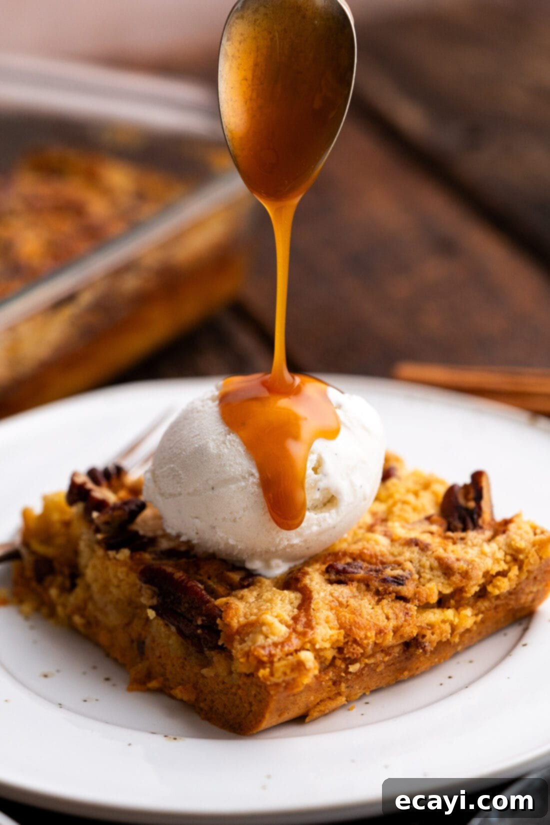 Effortless Pumpkin Spice Bake 3 Caramel sauce being drizzled over Pumpkin Dump Cake topped with ice cream