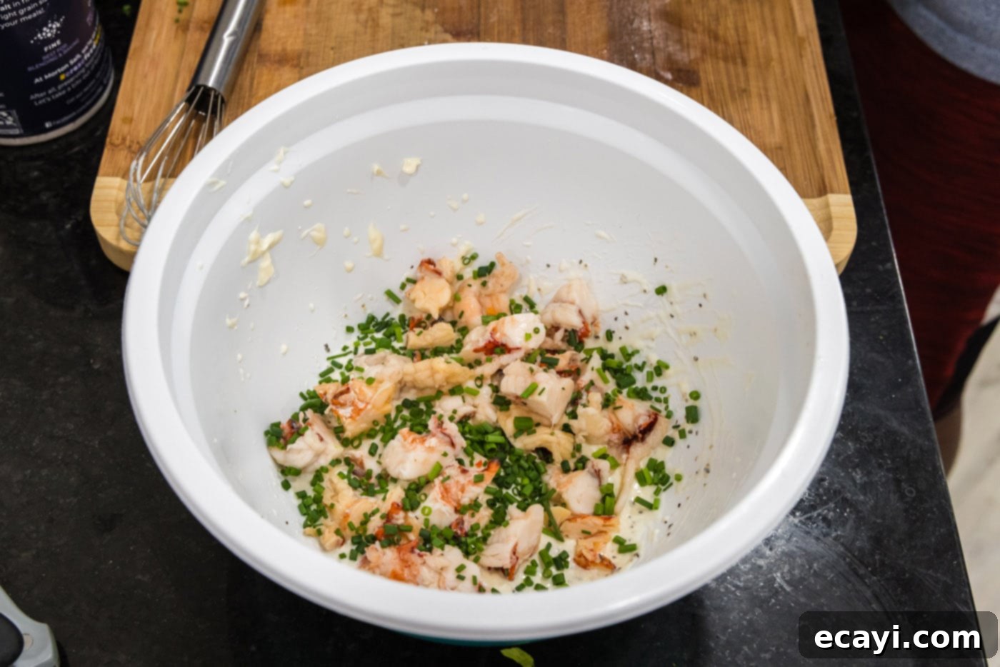 Classic Lobster Salad 7 chopped chives added to cooked lobster meat and dressing in a bowl