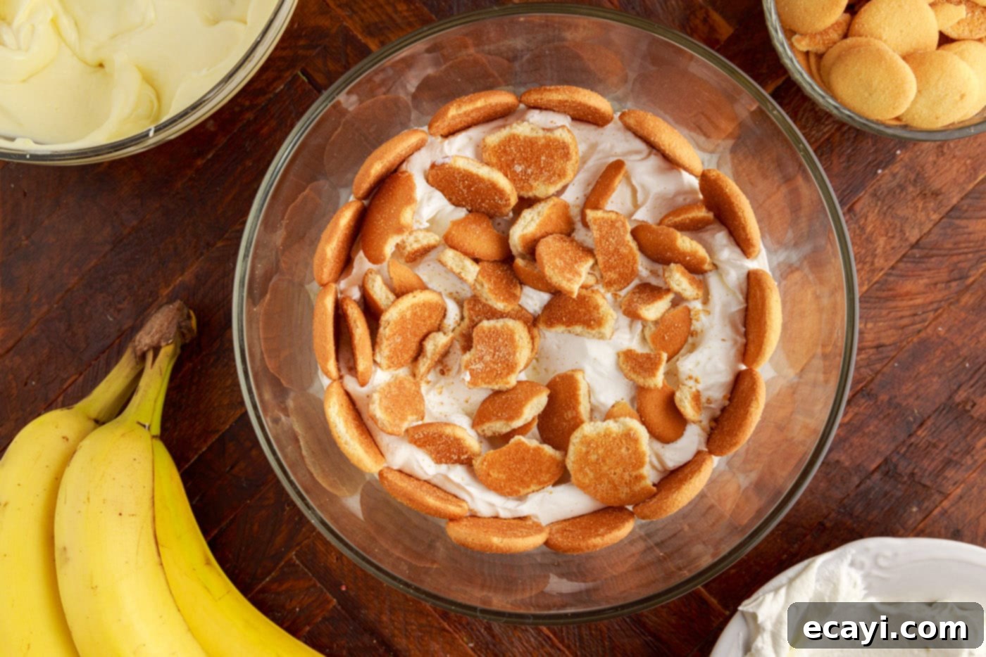 Decadent Banana Layers 13 crushed nilla wafers added on top of whipped cream layer in a trifle bowl