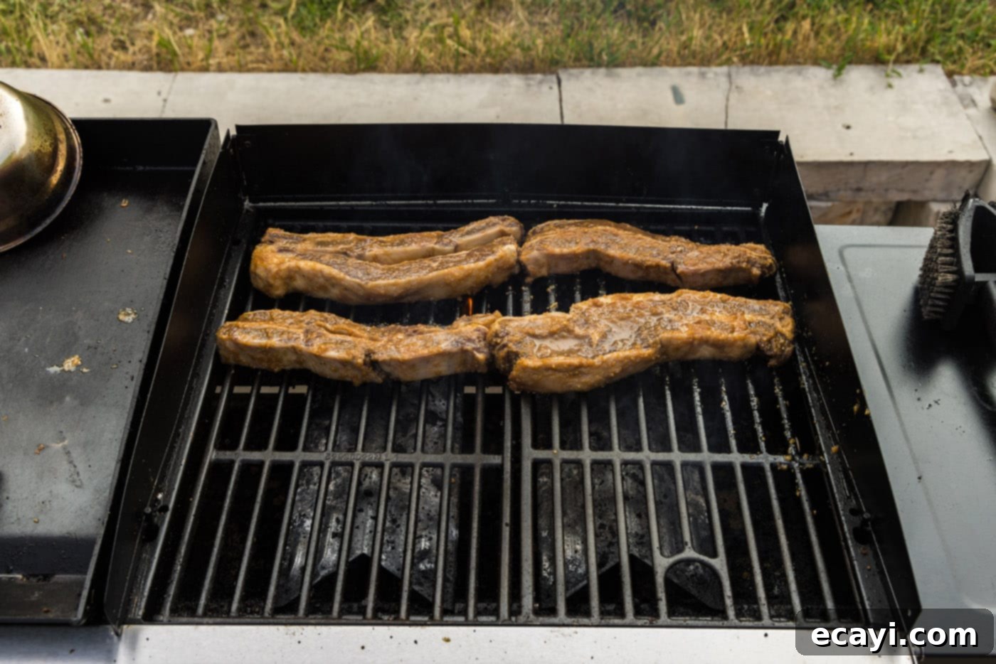 Fall-Off-The-Bone Korean Short Ribs 8 Thinly sliced Korean barbecue short ribs sizzling and cooking on a hot grill, showing early caramelization.