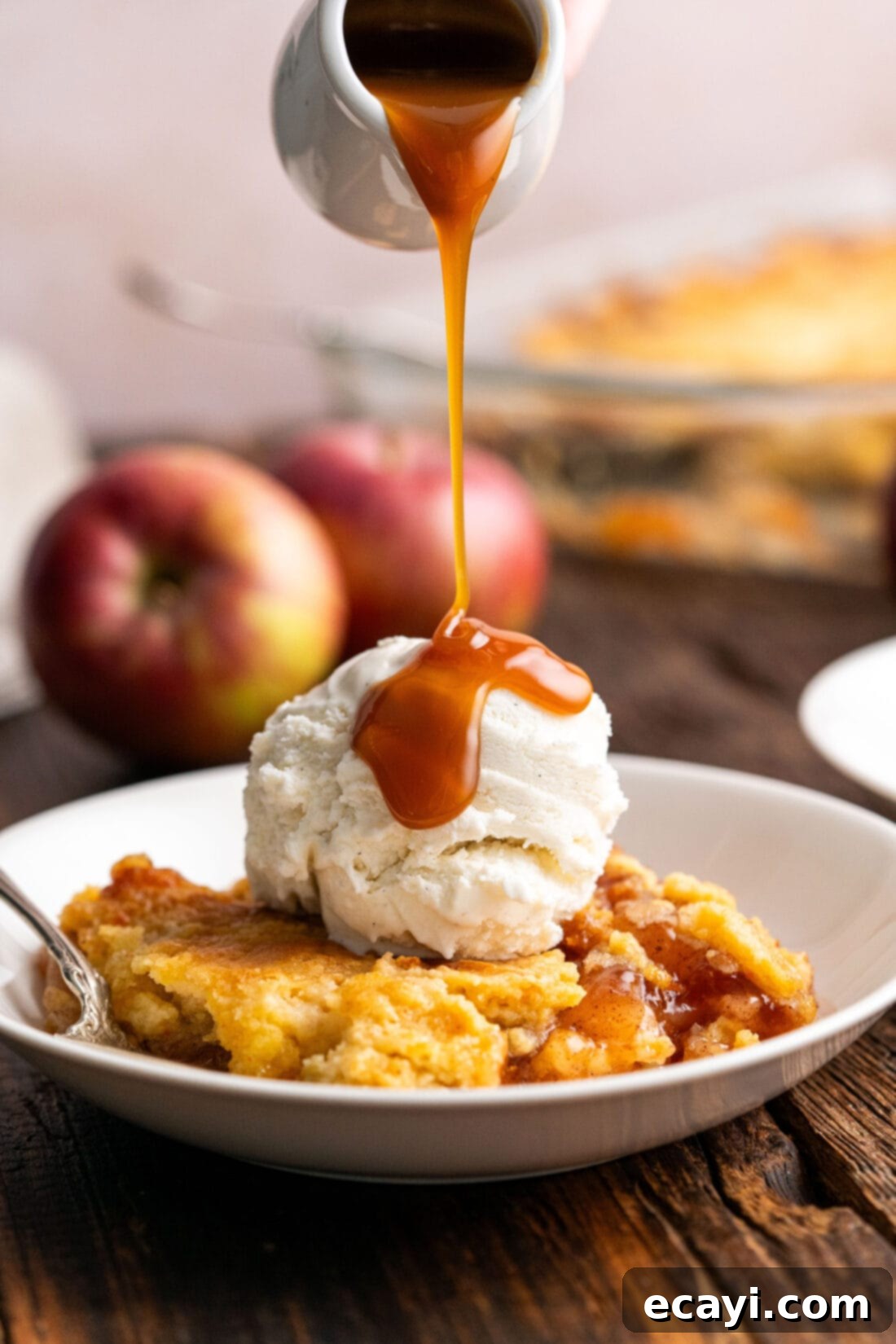 Gooey Caramel Apple Delight 2 Caramel sauce being drizzled over Caramel Apple Dump Cake topped with ice cream