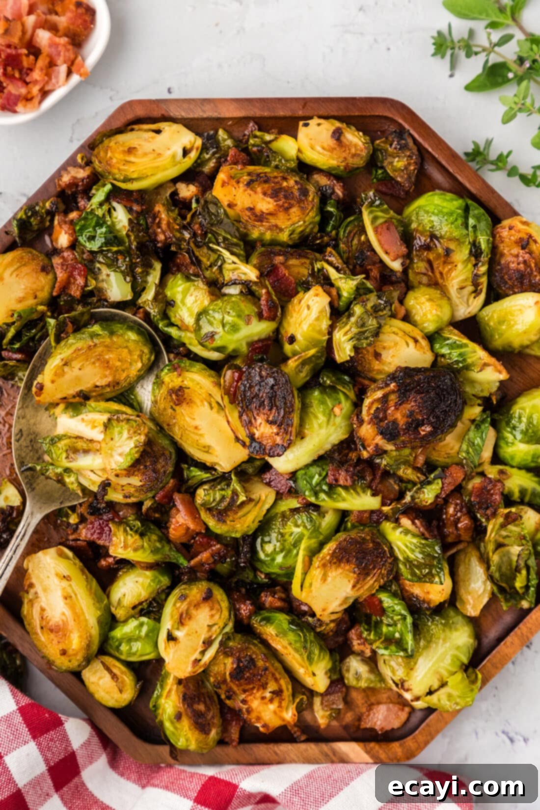Roasted Brussels Sprouts with Crispy Bacon and Glazed Pecans 2 Close up photo of Brussels Sprouts with Bacon, Shallots and Candied Pecans on a wooden platter, showcasing crispy bacon, glossy pecans, and perfectly cooked sprouts.