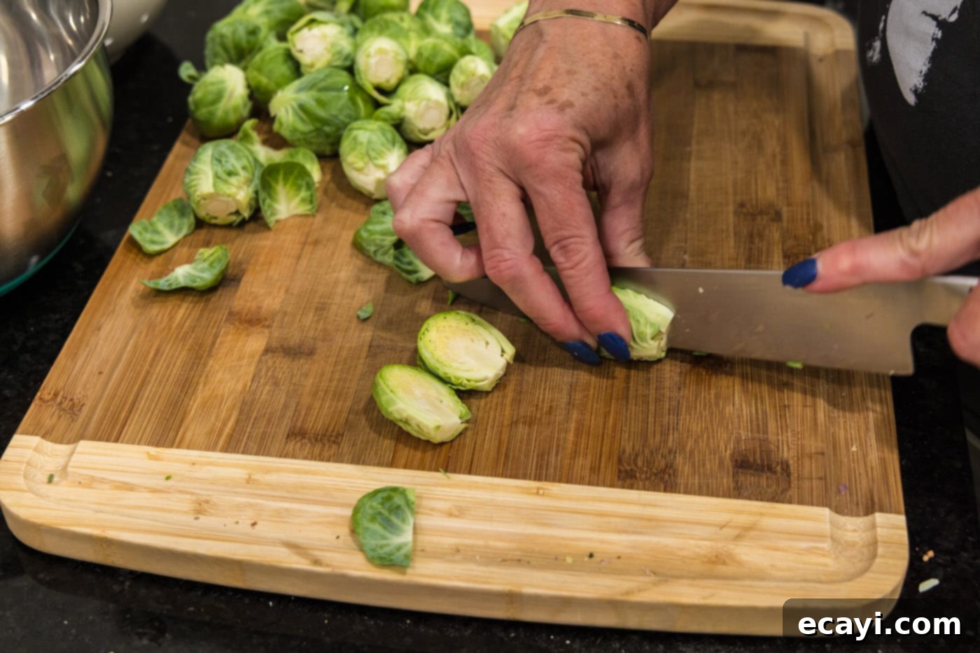 Roasted Brussels Sprouts with Crispy Bacon and Glazed Pecans 5 Slicing Brussels sprouts in half lengthwise, preparing them for cooking.