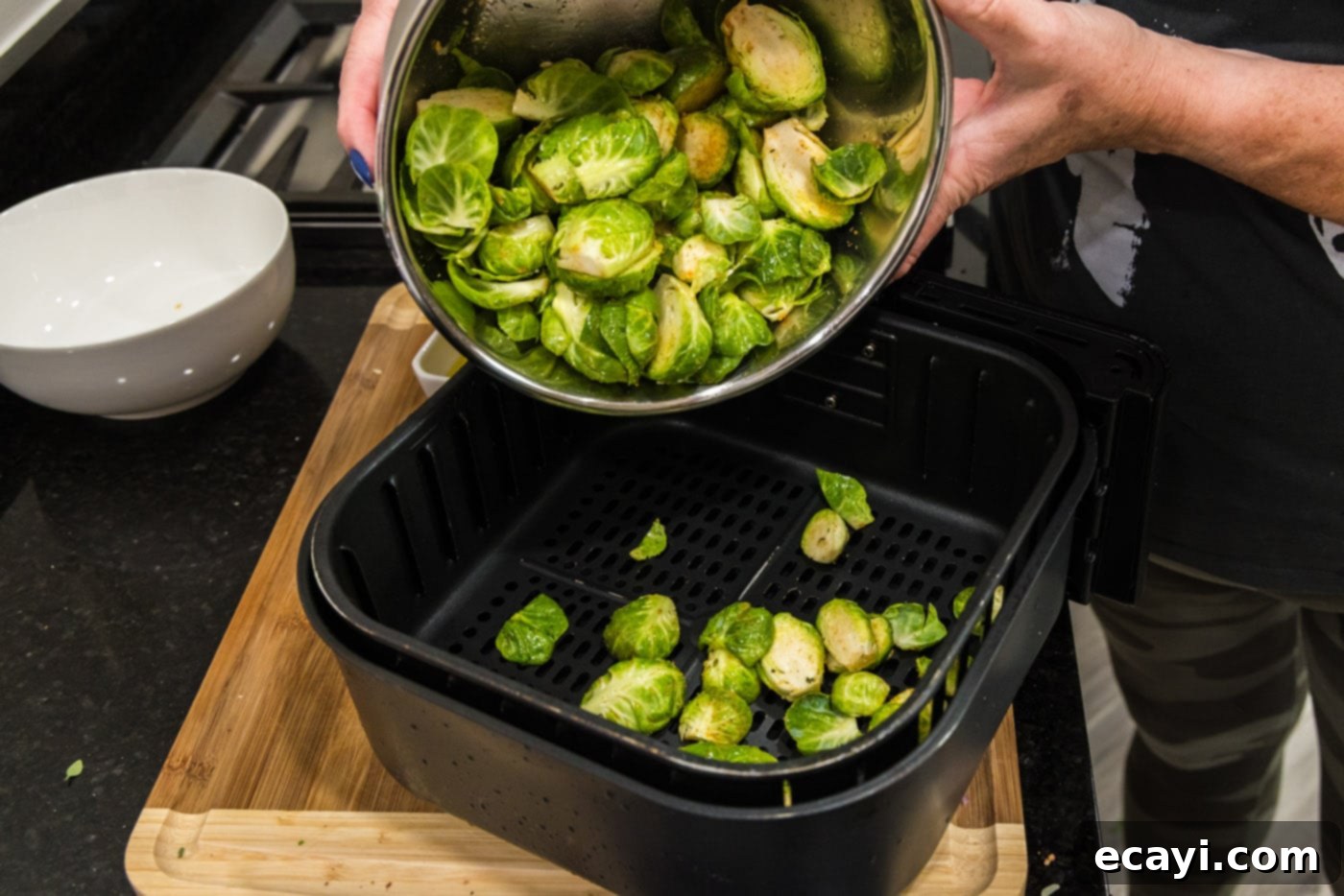 Roasted Brussels Sprouts with Crispy Bacon and Glazed Pecans 8 Adding seasoned Brussels sprouts to an air fryer basket for the initial cook.