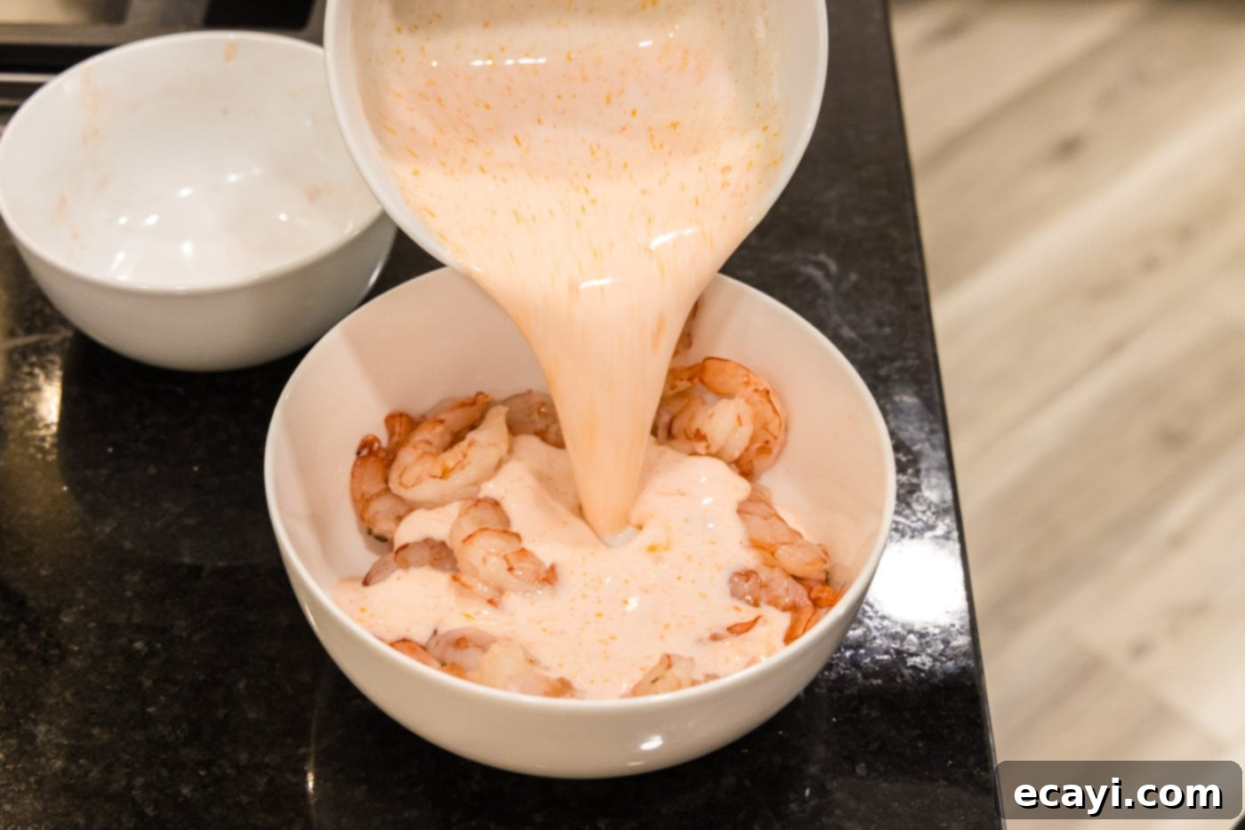 Bang Bang Shrimp 7 pouring buttermilk hot sauce mixture over shrimp in a bowl