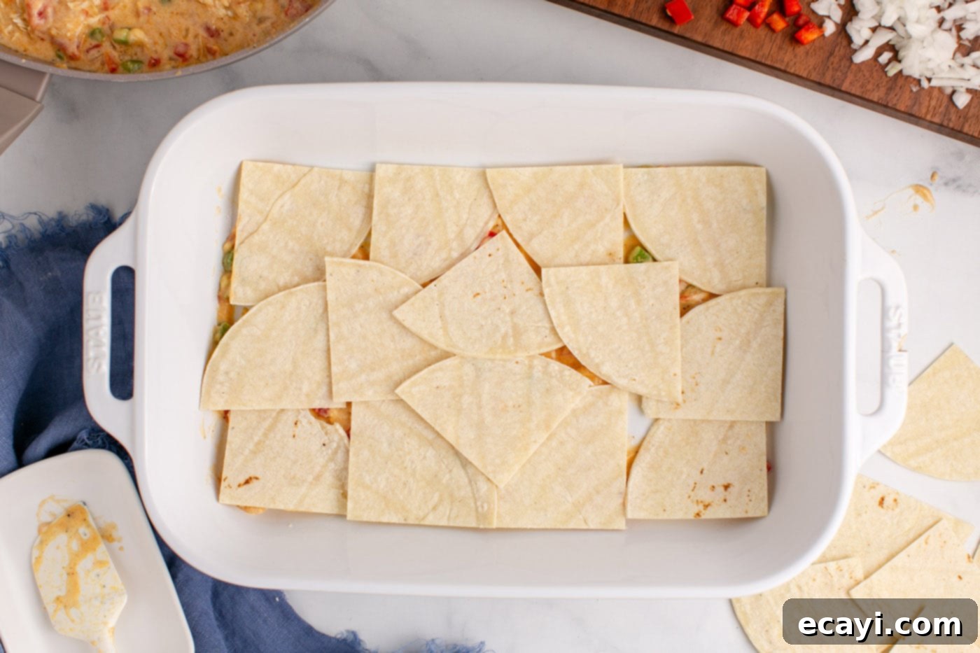 Comforting King Ranch Chicken Casserole 12 Quartered tortilla pieces layered over the sauce mixture in a baking dish.