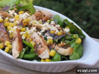 A close-up photo of a healthy and vibrant grilled chicken salad, artfully presented in a white dish, topped with a flavorful herbed tomato vinaigrette.