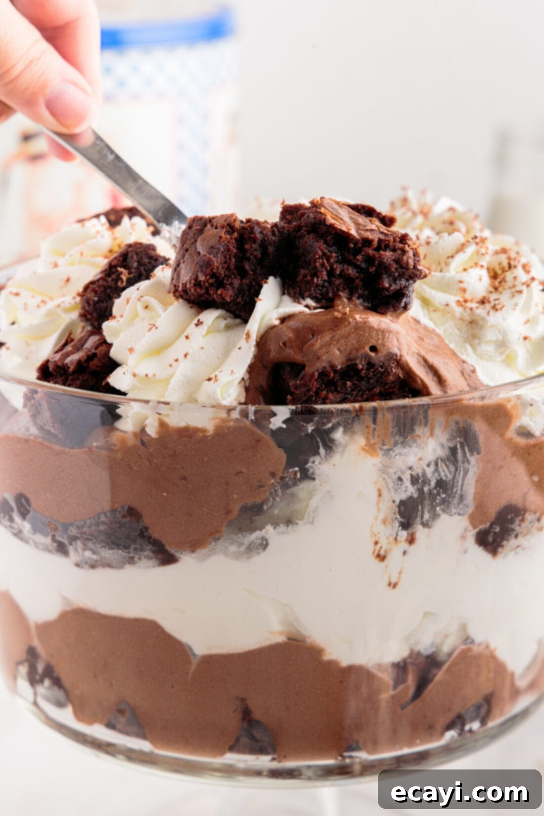 Decadent Brownie Trifle 3 A serving spoon dipped into the luscious layers of a Brownie Trifle, highlighting the fudgy brownies and creamy texture.