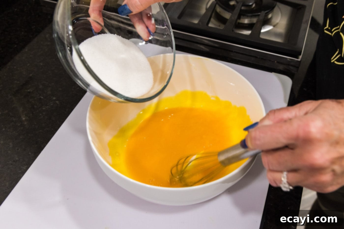 Creme Brulee 11 adding sugar to egg yolks in a bowl
