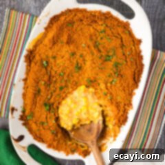 Creamy Baked Corn 16 Spoon removing Scalloped Corn from a baking dish, showcasing its creamy texture and golden topping