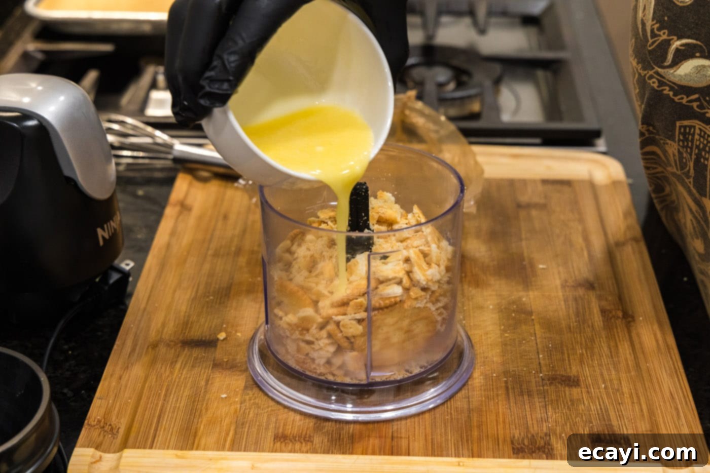 Creamy Baked Corn 5 Melted butter being poured into a food processor with crushed Ritz crackers for the topping