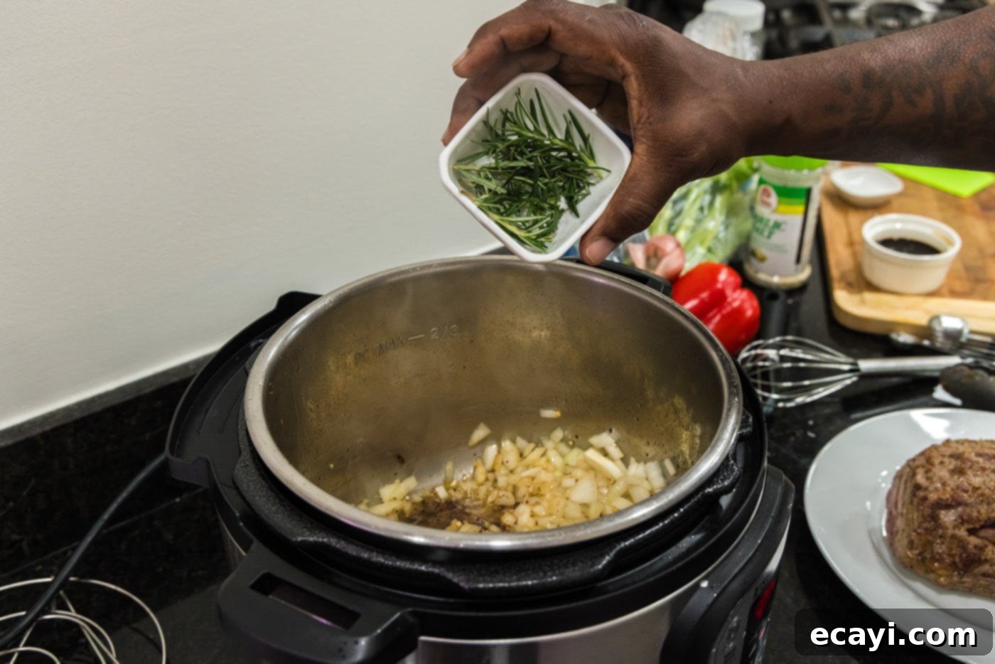 Effortless Instant Pot Roast Beef 9 adding rosemary to pot of onions and garlic