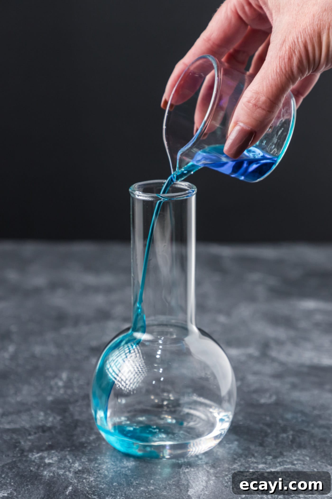 Amethyst Abyss Elixir 5 pouring blue curacao into cocktail glass