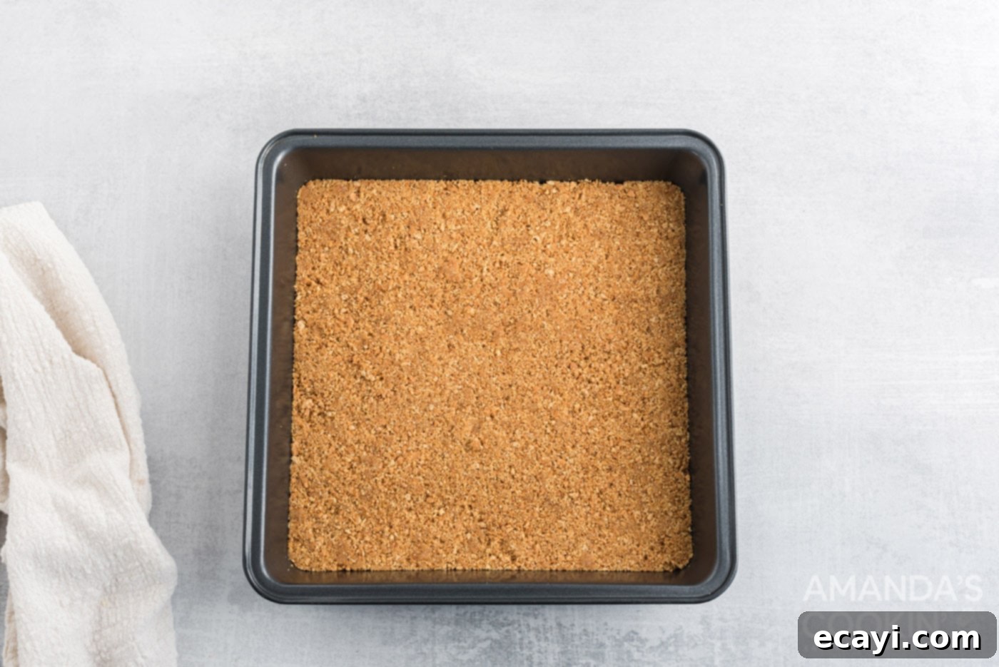 Pineapple Cloud Delight 5 A golden brown graham cracker crust firmly pressed into a square baking pan, cooling on a wire rack.
