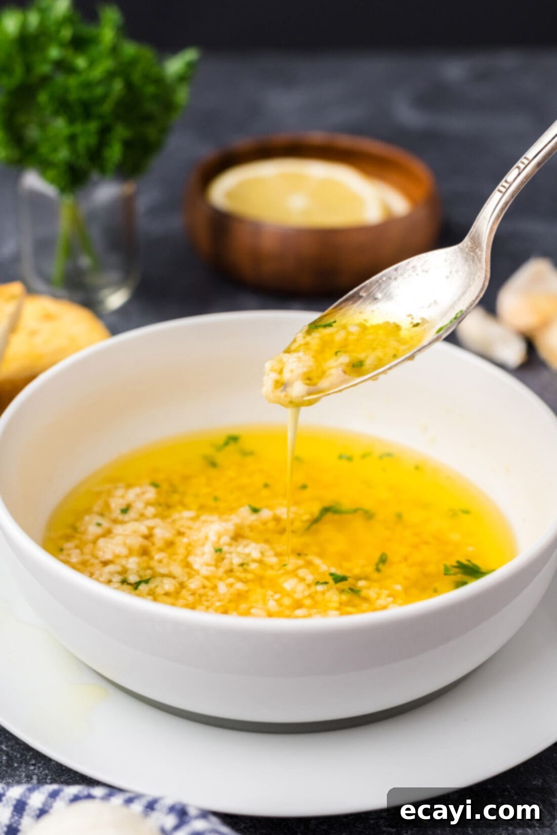 Liquid Gold Garlic Butter 11 A spoon elegantly drizzling golden Garlic Butter Sauce back into a bowl of the same sauce, showcasing its smooth, rich texture.