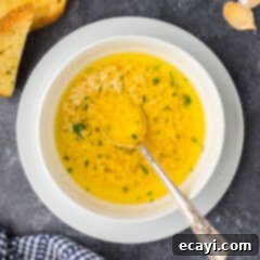 Liquid Gold Garlic Butter 12 Bowl of Garlic Butter Sauce with a spoon in it, showcasing its rich, golden color and smooth texture.