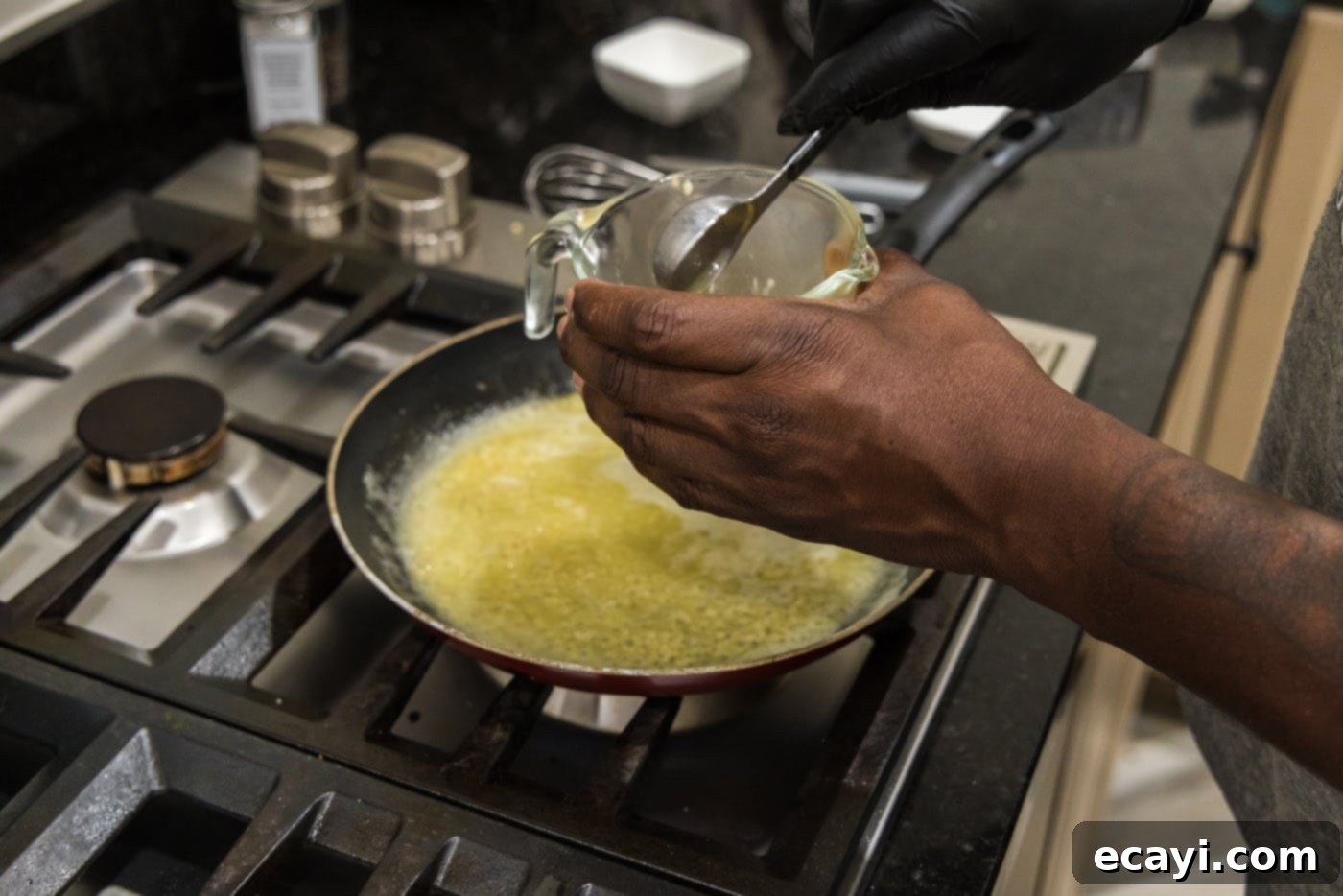Liquid Gold Garlic Butter 9 A measuring cup with a small amount of garlic butter sauce, cornstarch being added to create a slurry.
