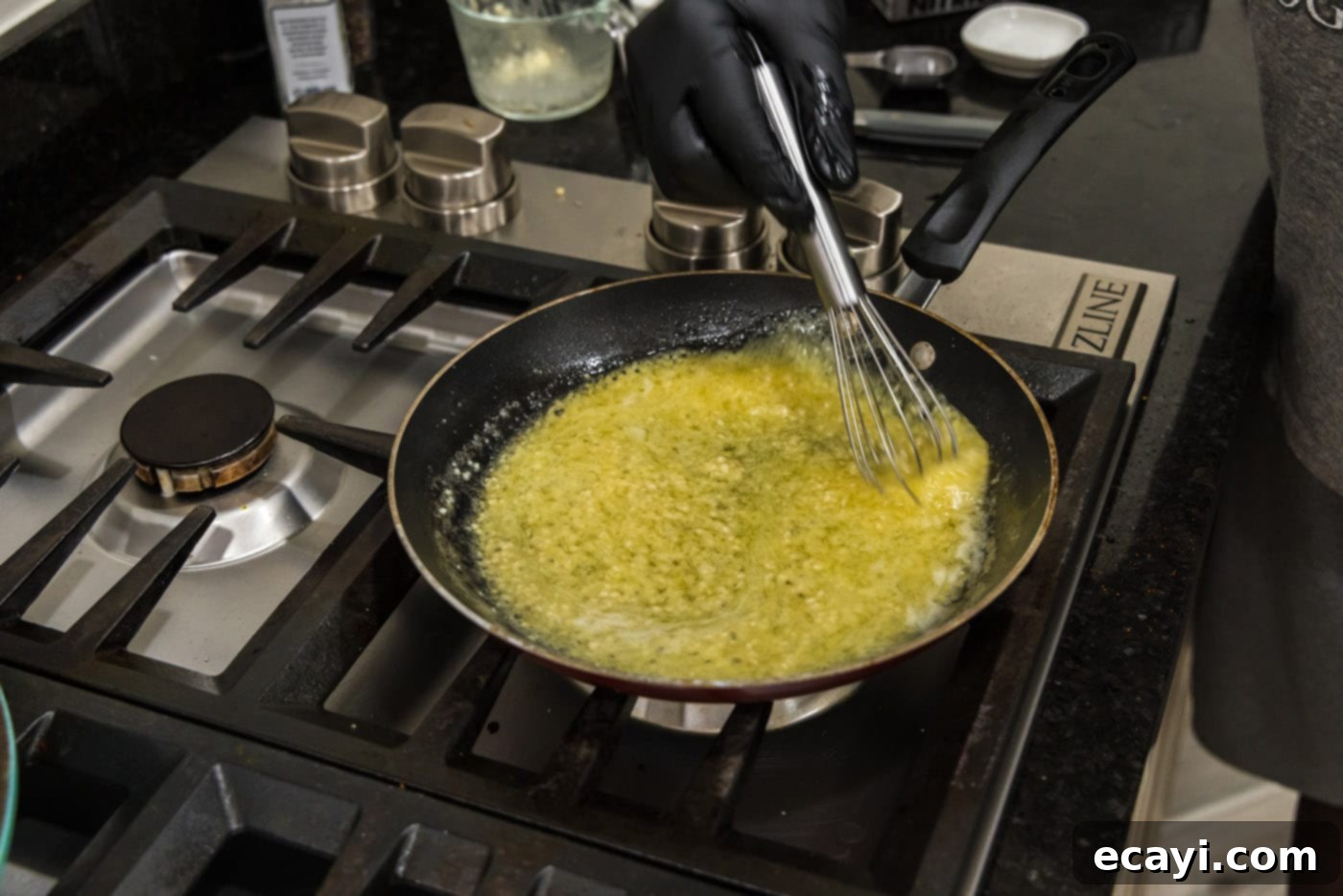 Liquid Gold Garlic Butter 10 The thickened garlic butter sauce being whisked in a skillet, now bubbly and ready for simmering.