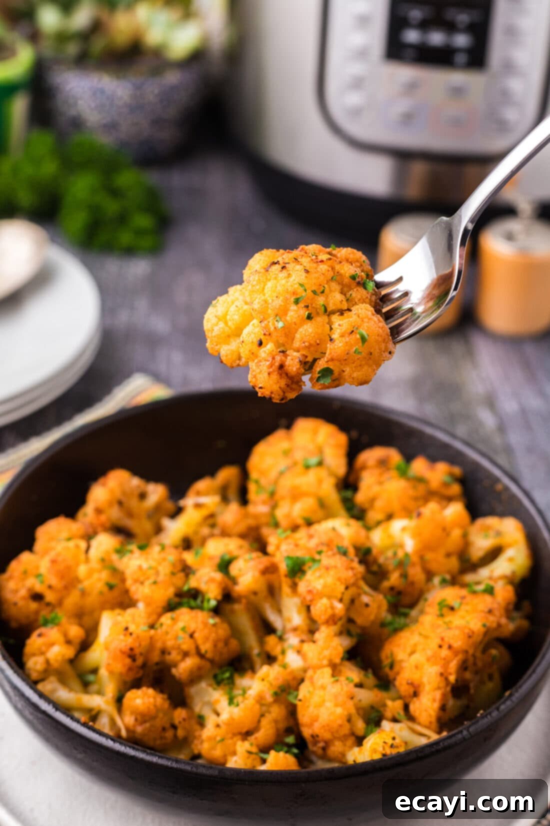 Effortless Instant Pot Cauliflower 3 Piece of Instant Pot Cauliflower on a fork held above a bowl of Instant Pot Cauliflower