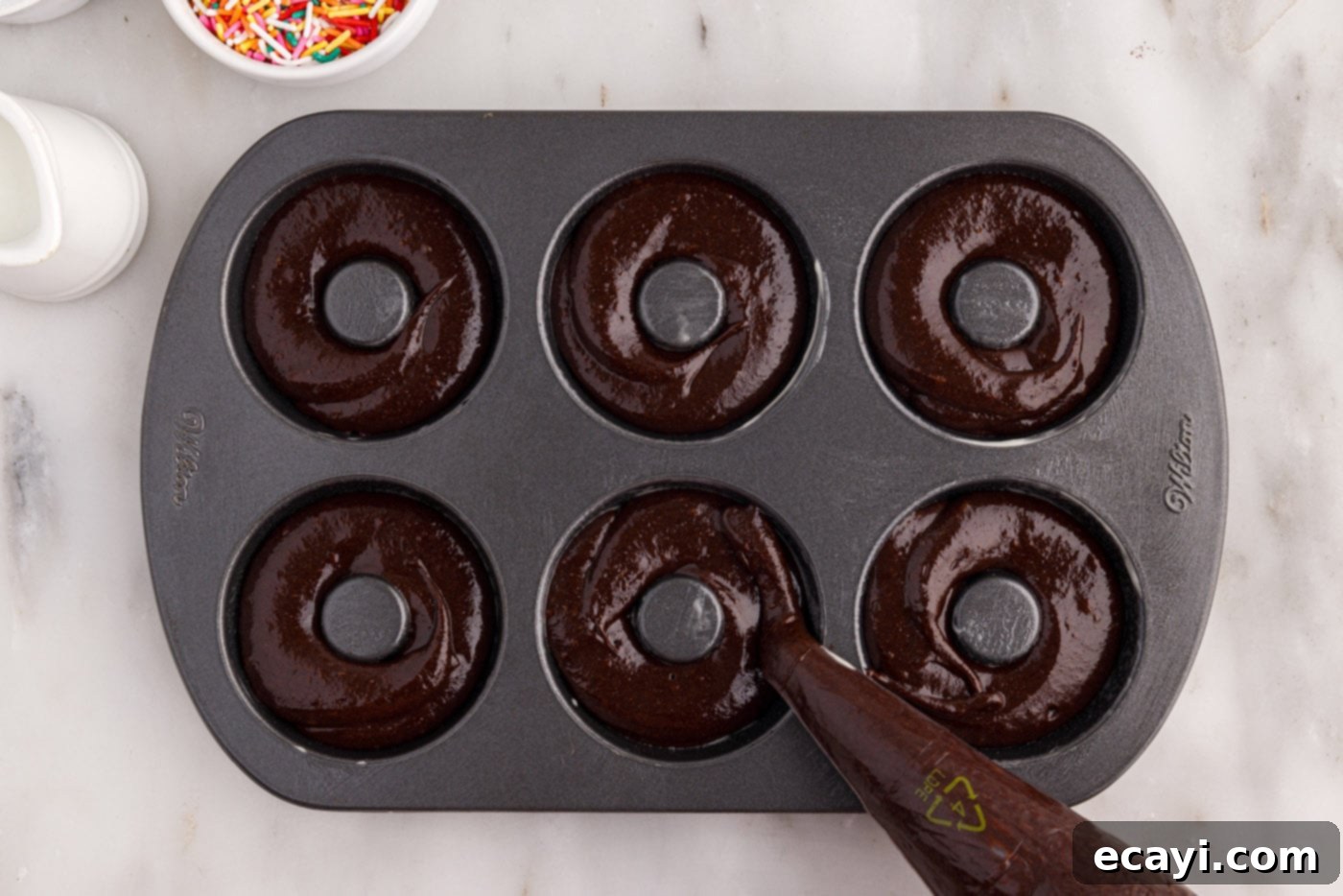 ChocoRings 11 piping bronut batter precisely into the cavities of a donut pan