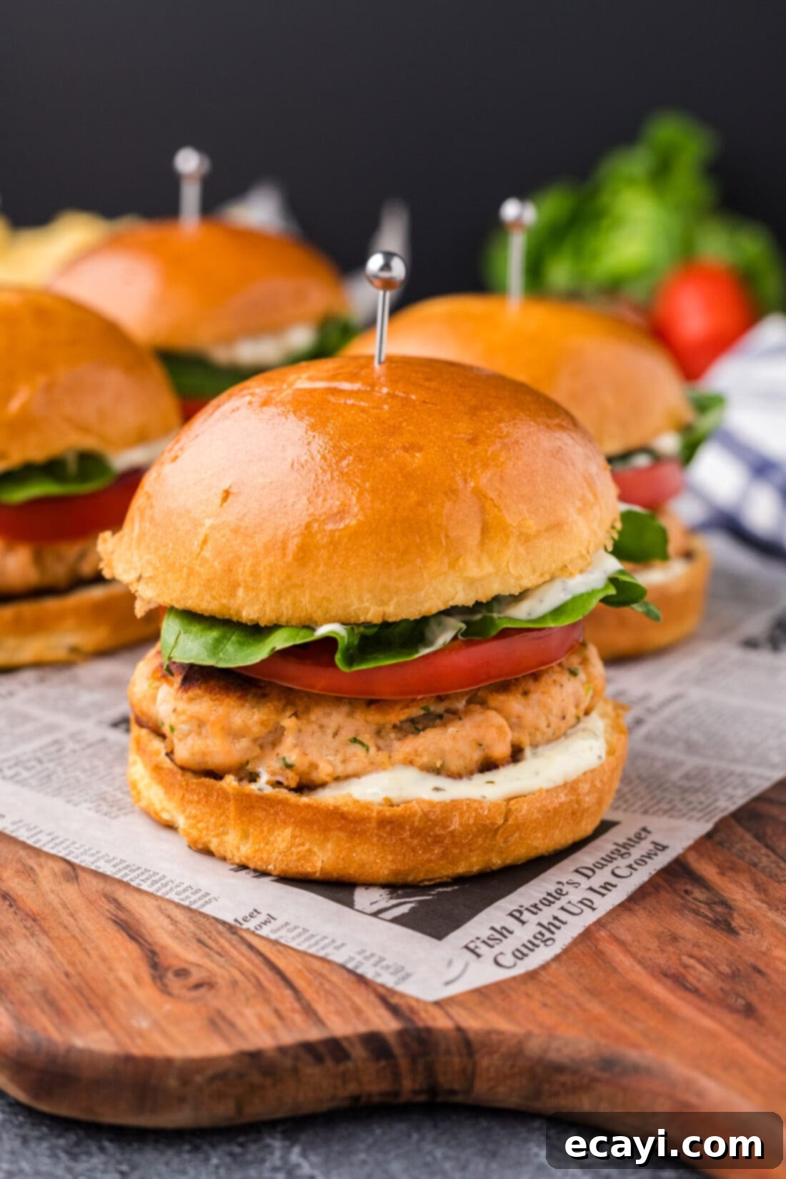 Delicious Salmon Burgers 2 Close up photo of pan-seared Salmon Burgers on a rustic wooden platter with fresh herbs